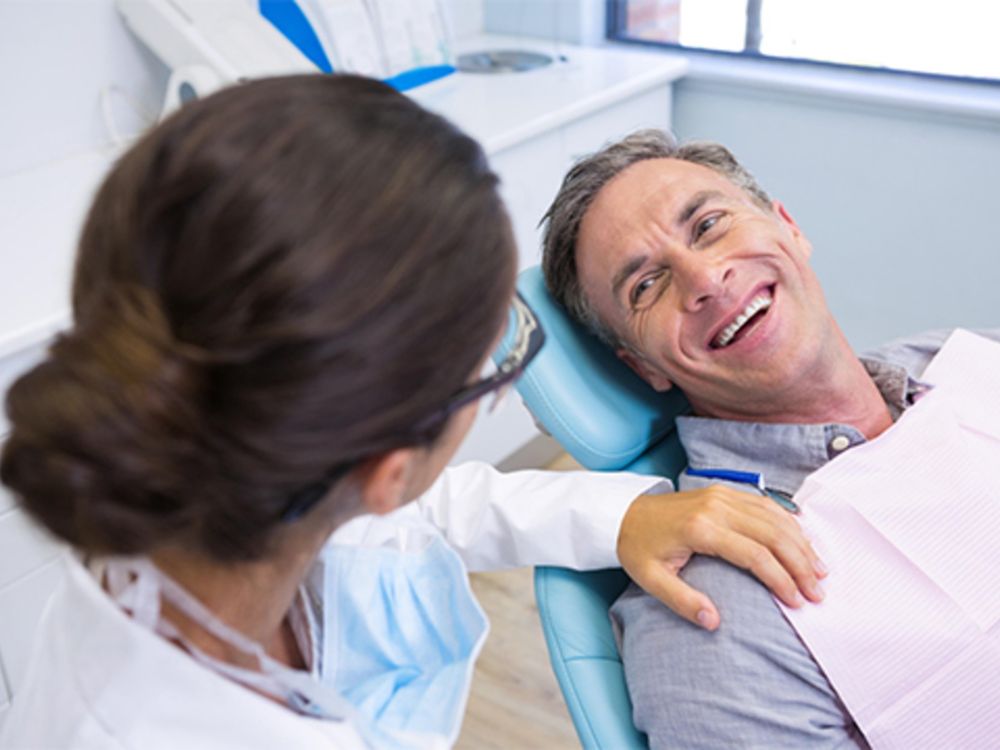 Paciente em atendimento odontológico com profissional, demonstrando o que é implante zigomático em contexto de tratamento dentário.