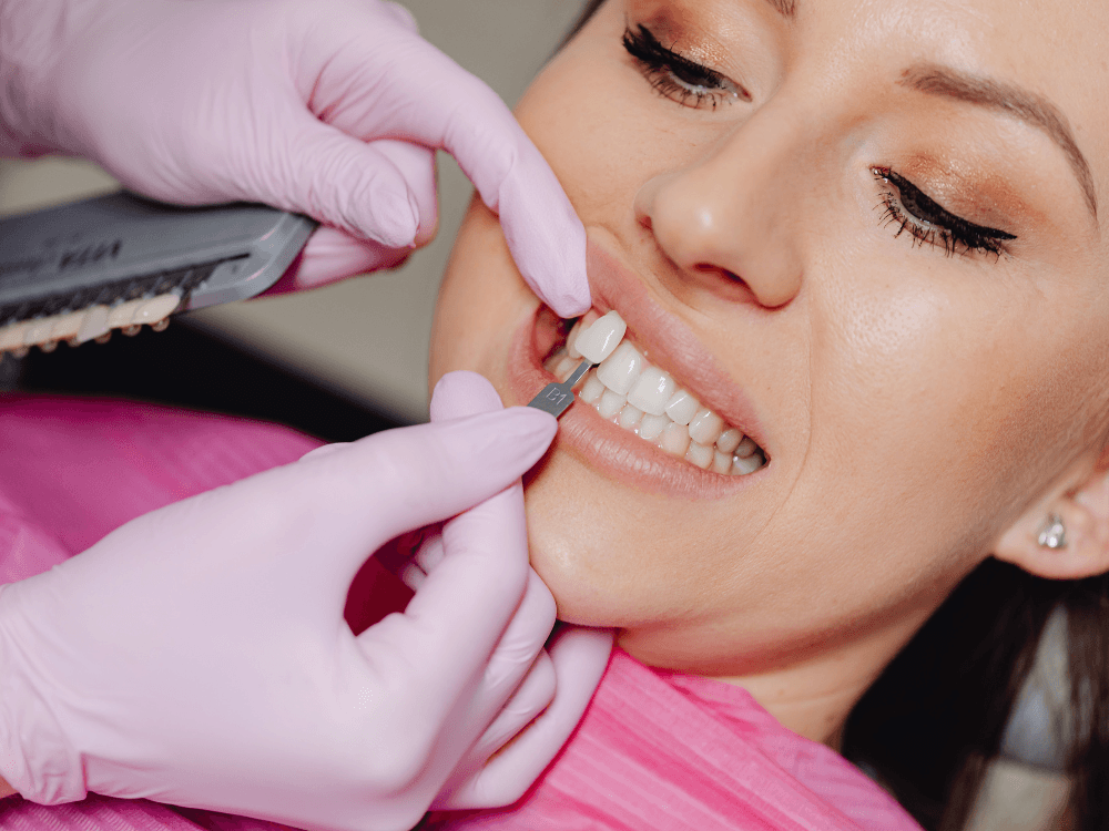 Dentista utiliza uma escala de cor junto aos dentes de uma paciente para definir características da futura prótese dentária